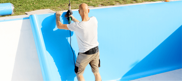 Hombre instando liner azul en piscina